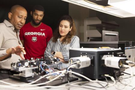 From left, professor Yohannes Abate talks with graduate students Marquez Howard and Neda Aghamiri about equipment used for nanoscale imaging and spectroscopy in his lab. (Photo taken by Andrew Davis Tucker/UGA prior to March 2020.)